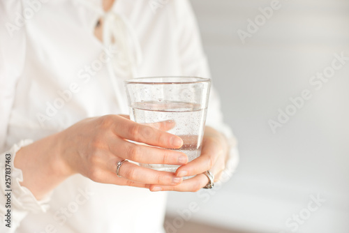 Glass of clean mineral water in woman's hands. Concept of environment protection, healthy drink. © Viktoria