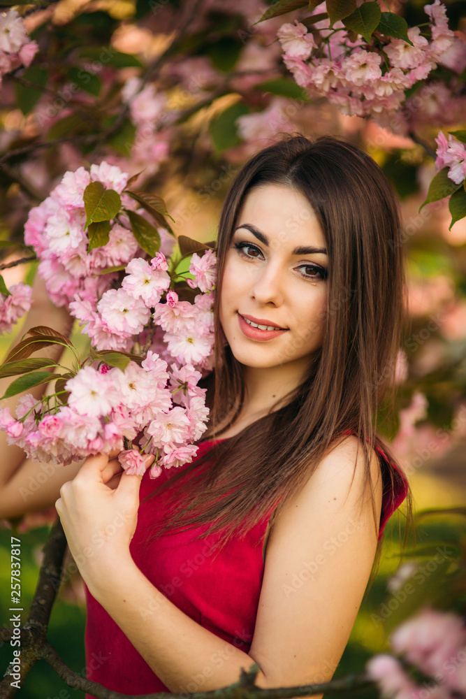 Portrait of beutiful girl in sakura tree. Sakura flowers surround the girl. Sakura branch by her face. Japanese tree Portrait of beutiful girl in sakura tree. Sakura flowers surround the girl. Sakura branch by her face. Japanese tree