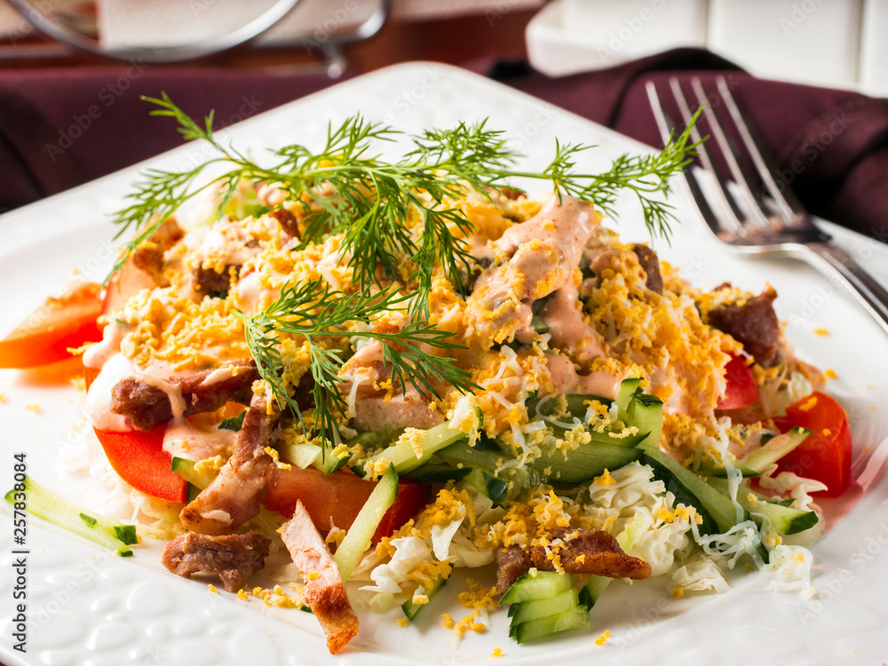 Close up view of salad with bacon, cucumber, pepper and dressed with egg. Salad in white plate on dark brown wooden table in restaurant Close up view of salad with bacon, cucumber, pepper and dressed with egg. Salad in white plate on dark brown wooden table in restaurant