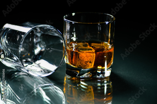 glasses of whiskey on a glass table with a lemon isolated on a black background, special stones for whiskey. glass objects