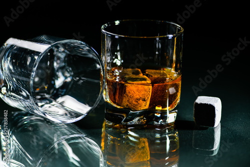 glasses made from whiskey on a glass table are isolated on a black background, special stones for whiskey. glass objects