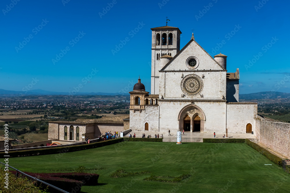 The lawn in front of St Francis of Assisi Church in Assisi, Umbria, Italy against a bright blue sky