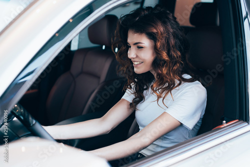 selective focus of cheerful curly woman sitting in automobile