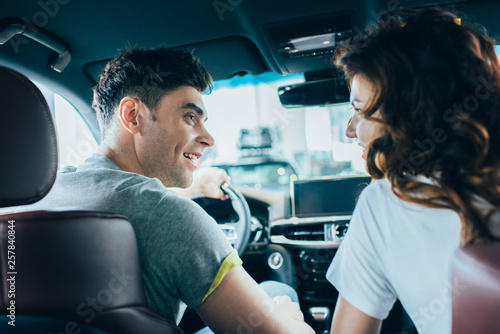 selective focus of handsome man looking at curly cheerful woman while sitting in automobile © LIGHTFIELD STUDIOS