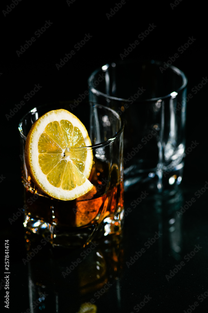 glasses of whiskey on a glass table with a lemon isolated on a black  background, special stones for whiskey. glass objects Stock Photo | Adobe  Stock