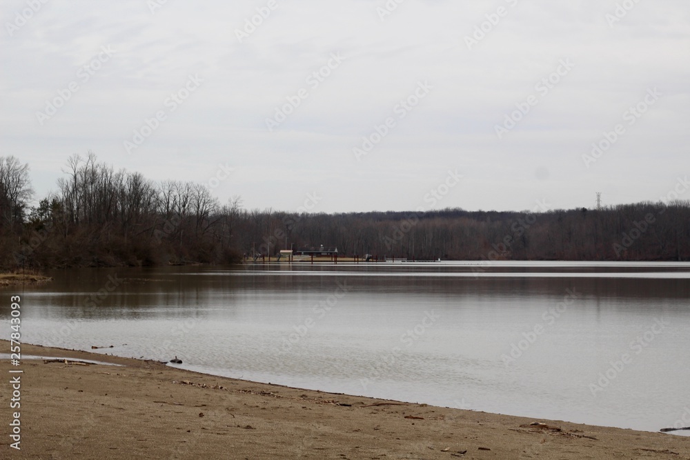 A view of the lake from the beach shoreline on a cloudy day.