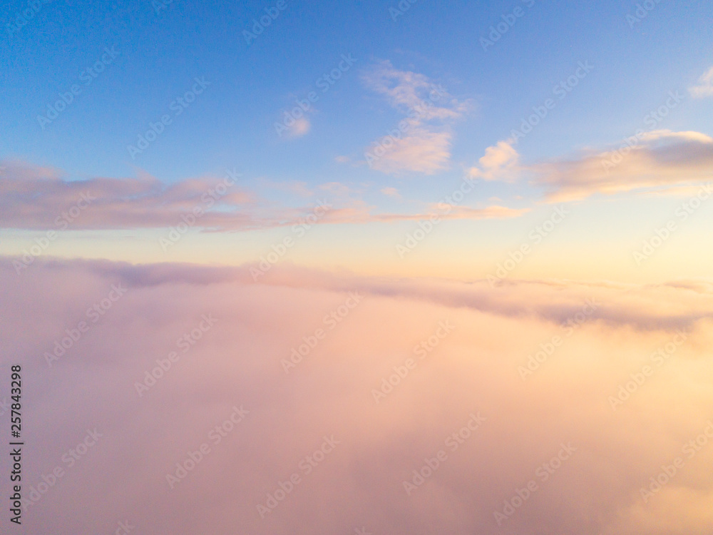 Aerial view White clouds in blue sky. Top view. View from drone. Aerial bird's eye view. Aerial top view cloudscape. Texture of clouds. View from above. Sunrise or sunset over clouds