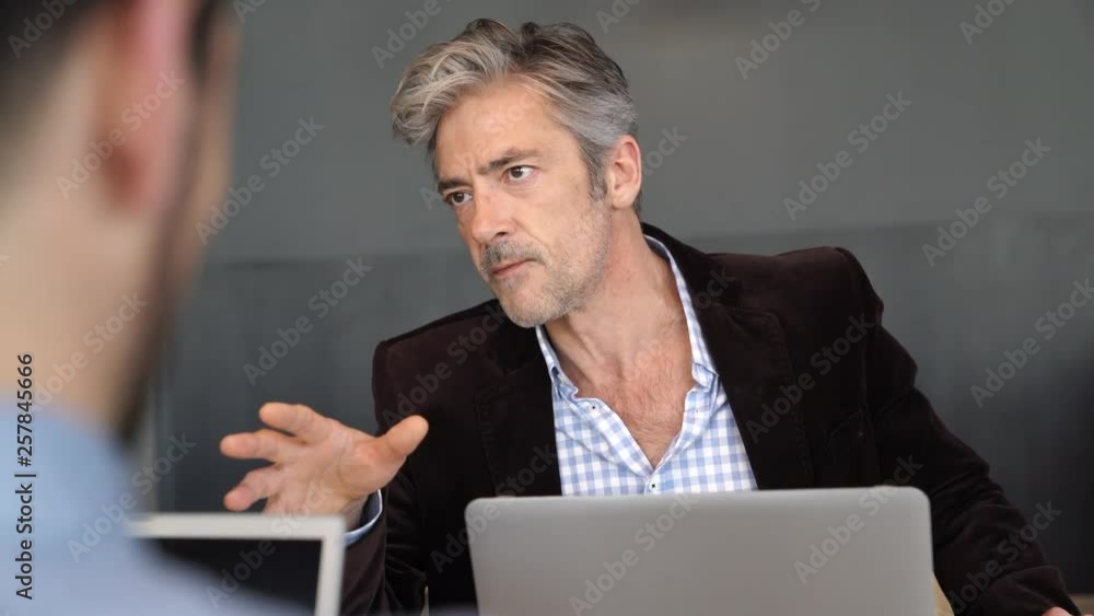 Mature manager briefing team before meeting in modern work space Mature manager briefing team before meeting in modern work space