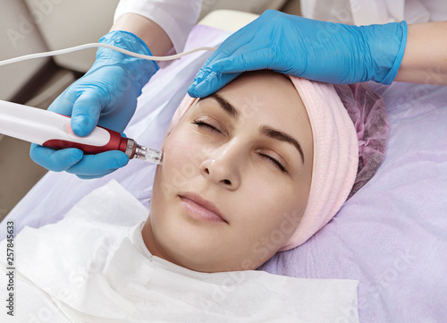 Enjoy your stay in beauty salon. Young woman closing her eyes during  rejuvenation procedure. Facial skin care. 