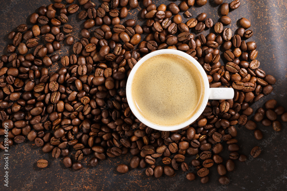 Coffee cup on roasted coffee beans. Dark background, sun rays. Coffee cup on roasted coffee beans. Dark background, sun rays.