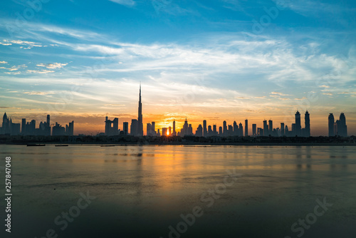 Morning or sunrise in Dubai. Dawn over Burj Khalifa. Beautiful colored cloudy sky over downtown Dubai. Solar path on sea comes from Burj Khalifa