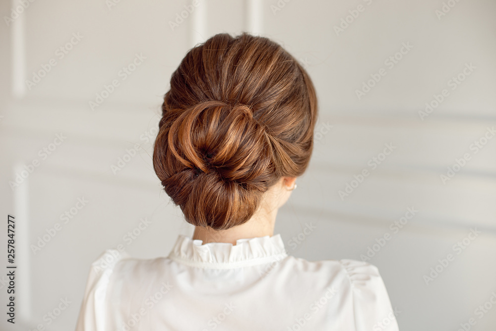 Rear view of female hairstyle medium bun with dark hair.