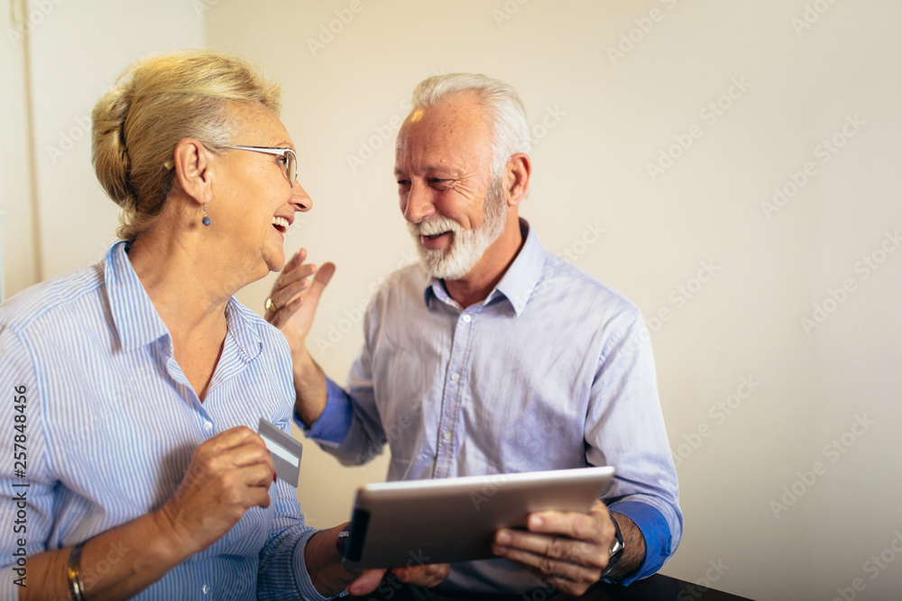 Modern senior couple shopping online with tablet and credit card Modern senior couple shopping online with tablet and credit card