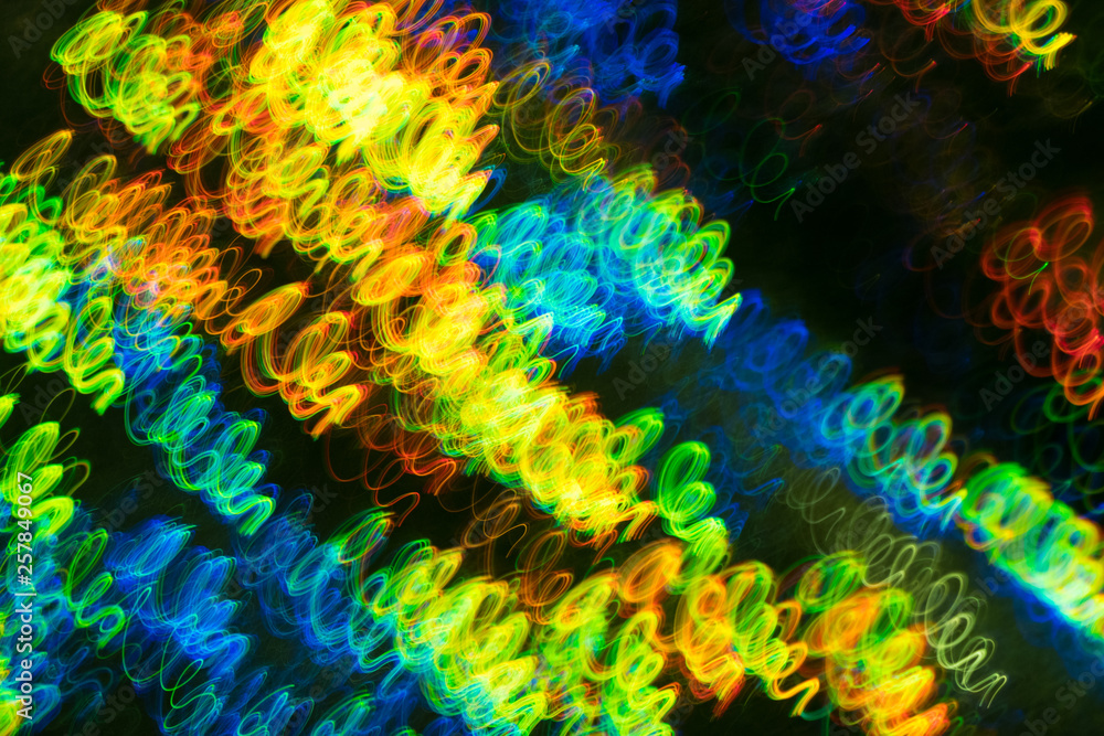 Blurred neon lights in motion. Thin curved multicolor lines on dark background. Lens flare effect.