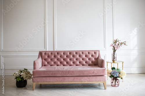Luxury rich living room interior design with elegant classic furniture and wall decorations. Large light white room with big window