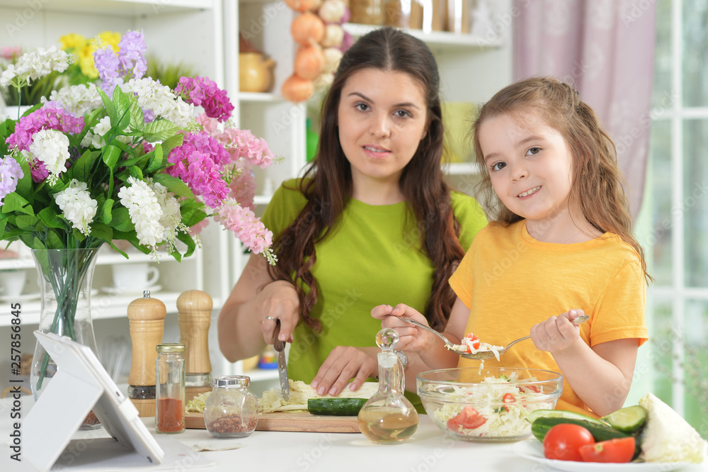 Cute little girl with her mother cooking together Cute little girl with her mother cooking together