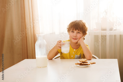 child boy drinks milk and eats cookies home kitchen 
