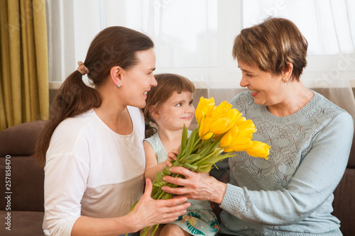 Portrait of happy grandma, mother and child daughter with flowers  in the home. Family, holidays and people concept. Happy women's day!