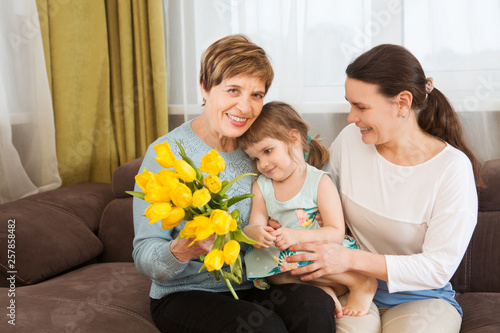 Portrait of happy grandma, mother and child daughter with flowers in the home. Family, holidays and people concept. Happy women's day!