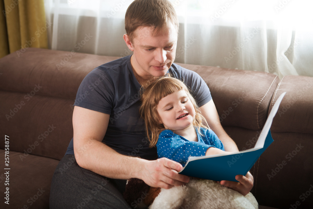 Father reading a story to his child daughter. happy family time together at home. Father reading a story to his child daughter. happy family time together at home.