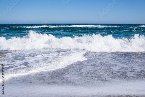 Sea waves on the beach, bright blue water