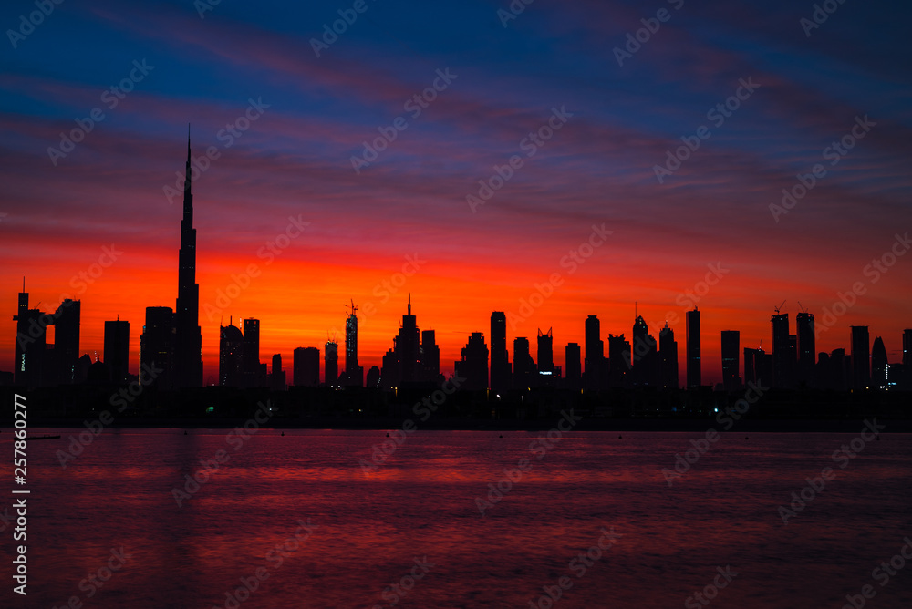 Mythical bloody red sky over Dubai. Dawn, morning, sunrise or dusk over Burj Khalifa. Beautiful colored cloudy sky over Dubai downtown . Glow over buildings or skyscrapers