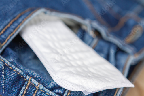 Woman hygiene protection, close-up panty liners on jeans background. Women's health. Feminine pads. Critical days. Discrete panty liner or pad for woman. Intimate hygiene. Daily panty liners.