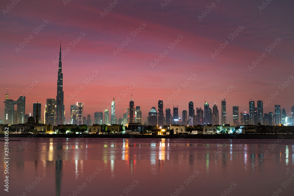 Obraz premium Dubai in night city lights or dusk. Dawn over Burj Khalifa. Nightly Dubai downtown. View from sea to Dubai quay