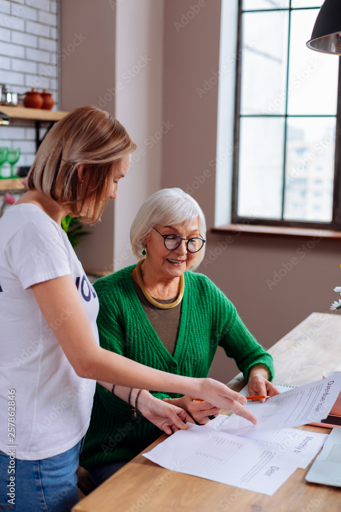 Obraz premium Beaming dame on pension considering loan application with granddaughter assistance