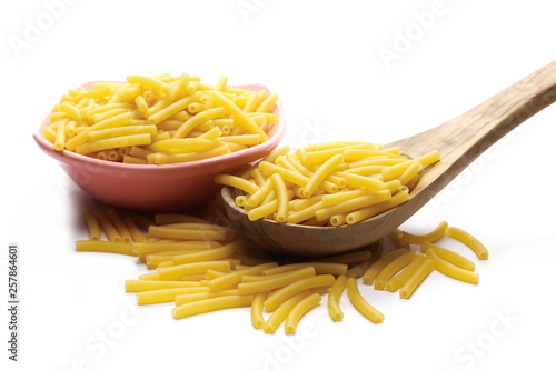 Macaroni, raw pasta in bowl with wooden spoon isolated on white background