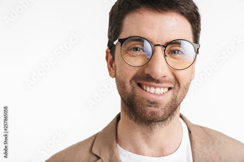 Fototapeta Naklejka Na Ścianę i Meble -  Image of positive man 30s with stubble wearing jacket and eyeglasses smiling on camera
