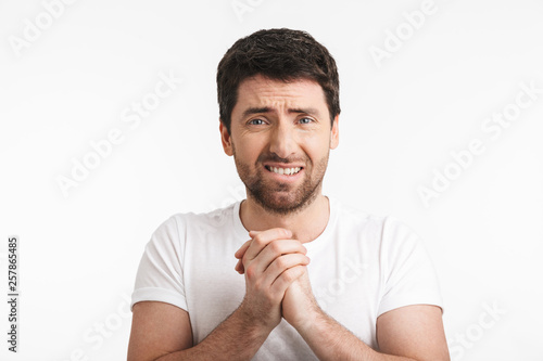 Image of stressful man 30s with bristle in casual t-shirt clenching fists with tension