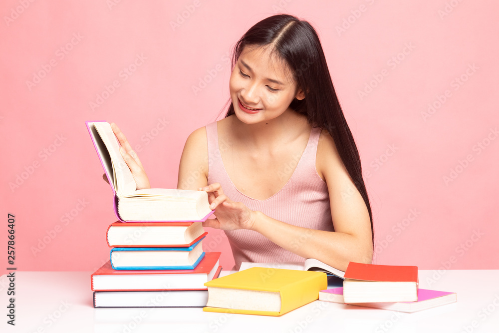 Young Asian woman read a book with books on table. Young Asian woman read a book with books on table.