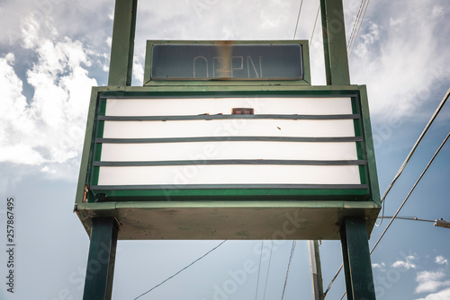 An old, dilapitated and empty changeable letter sign board on a street.