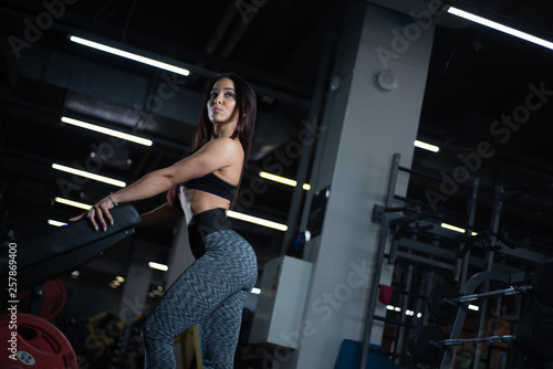 Fitness girl posing in the gym, showing off her body and relaxing after a workout