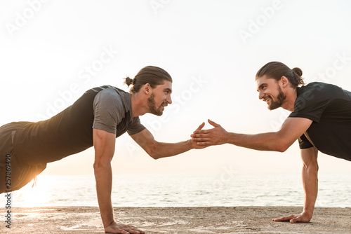 Two twin brothers doing exercises at the beach together