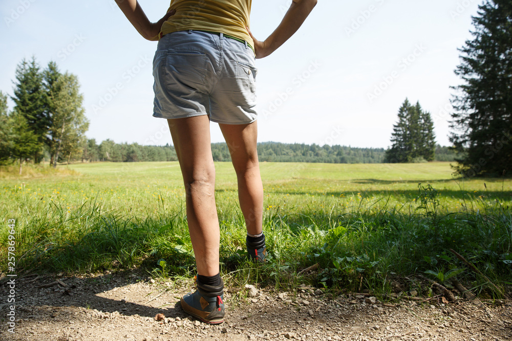 Woman with painful varicose veins on legs resting on a walk through nature.