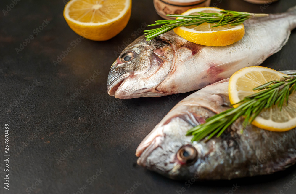 two fresh raw Dorado fish with spices and olive oil on a stone background. two fresh raw Dorado fish with spices and olive oil on a stone background.