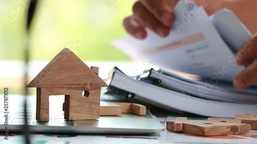 Property home model for loan real estate to buy new for family or mortgage investment concept: Wooden house models on laptop computer with businessman and chart report documents contact customer