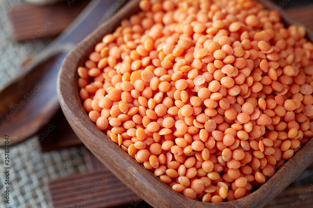 Raw uncooked red lentils (lens culinaris) in wooden bowl Raw uncooked red lentils (lens culinaris) in wooden bowl