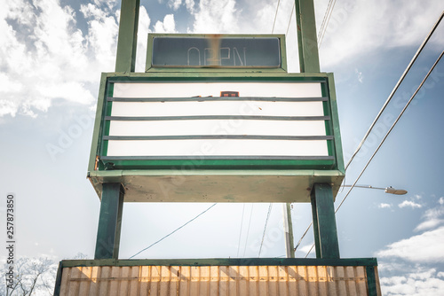An old, dilapitated and empty changeable letter sign board on a street.
