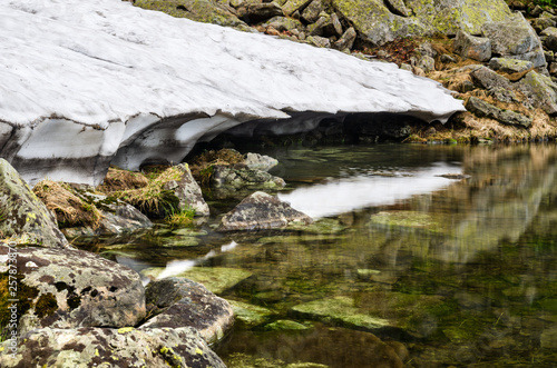 Melting snowfield and mountain lake Brebeneskul in Carpathian mountains, Ukraine photo