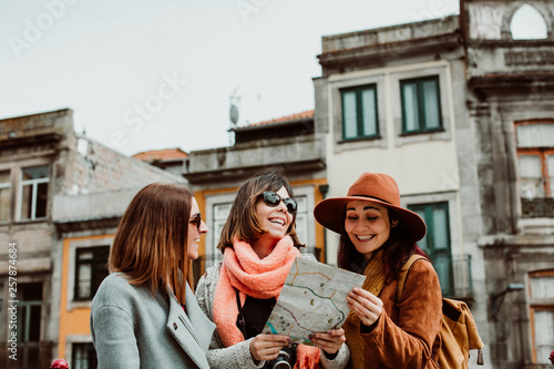 .Three beautiful and funny women traveling together in Porto, Portugal. Standing together carefree and relaxed using their map to locate themselves. Lifestyle. Travel photography © lubero