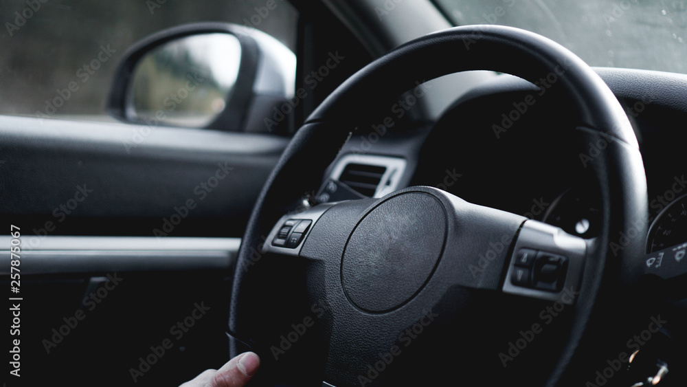 Interior view of car with black salon. Close-up Of A Man Hands Holding Steering Wheel While Driving Car