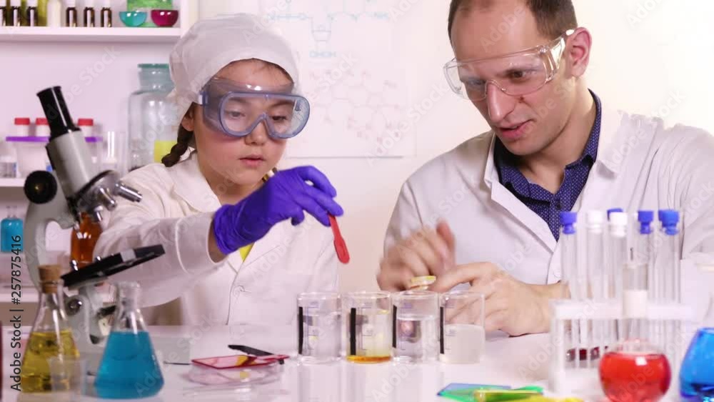 Chemistry teacher and schoolgirl conducting experiments with chemical reagents in a chemical laboratory Chemistry teacher and schoolgirl conducting experiments with chemical reagents in a chemical laboratory