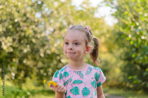 A happy cute little girl with dandelions on a sunny glade.