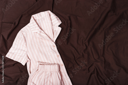 Pink pajamas for Girls on chocolade colored sheet. Soft cotton nightwear. Copy space. Top view. Flat lay. © yrabota
