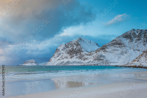 Crystal clear winter beach with mountains in the background, beautiful sunset in Norway