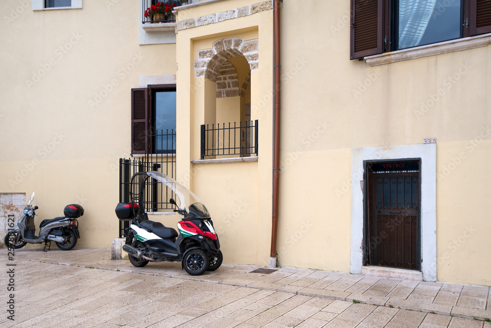 Early morning in old city in Italy, Bari. Scooters parked next to apartment buildings with flower decorated balconies and facades. 