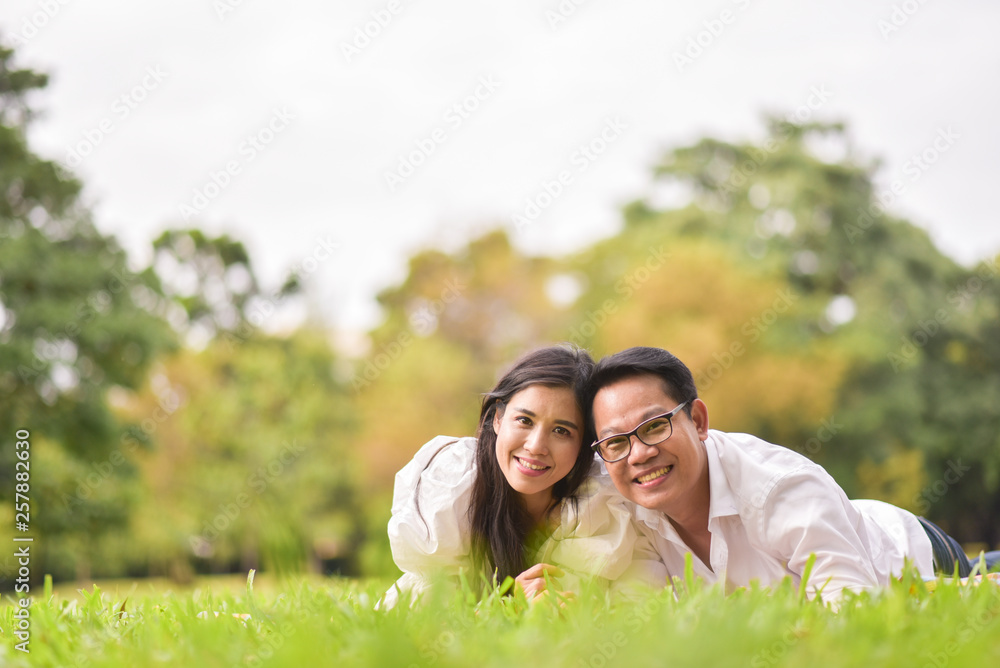 Portrait of happy young asian couple laying on grass In public park. Portrait of happy young asian couple laying on grass In public park.